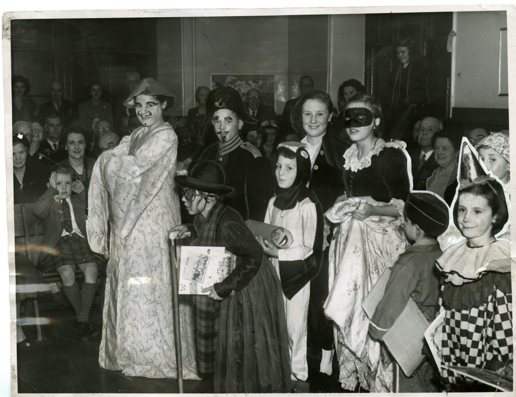 A group of young people in their Halloween costumes ready to perform various acts in a night of guising. Halloween, 1951.