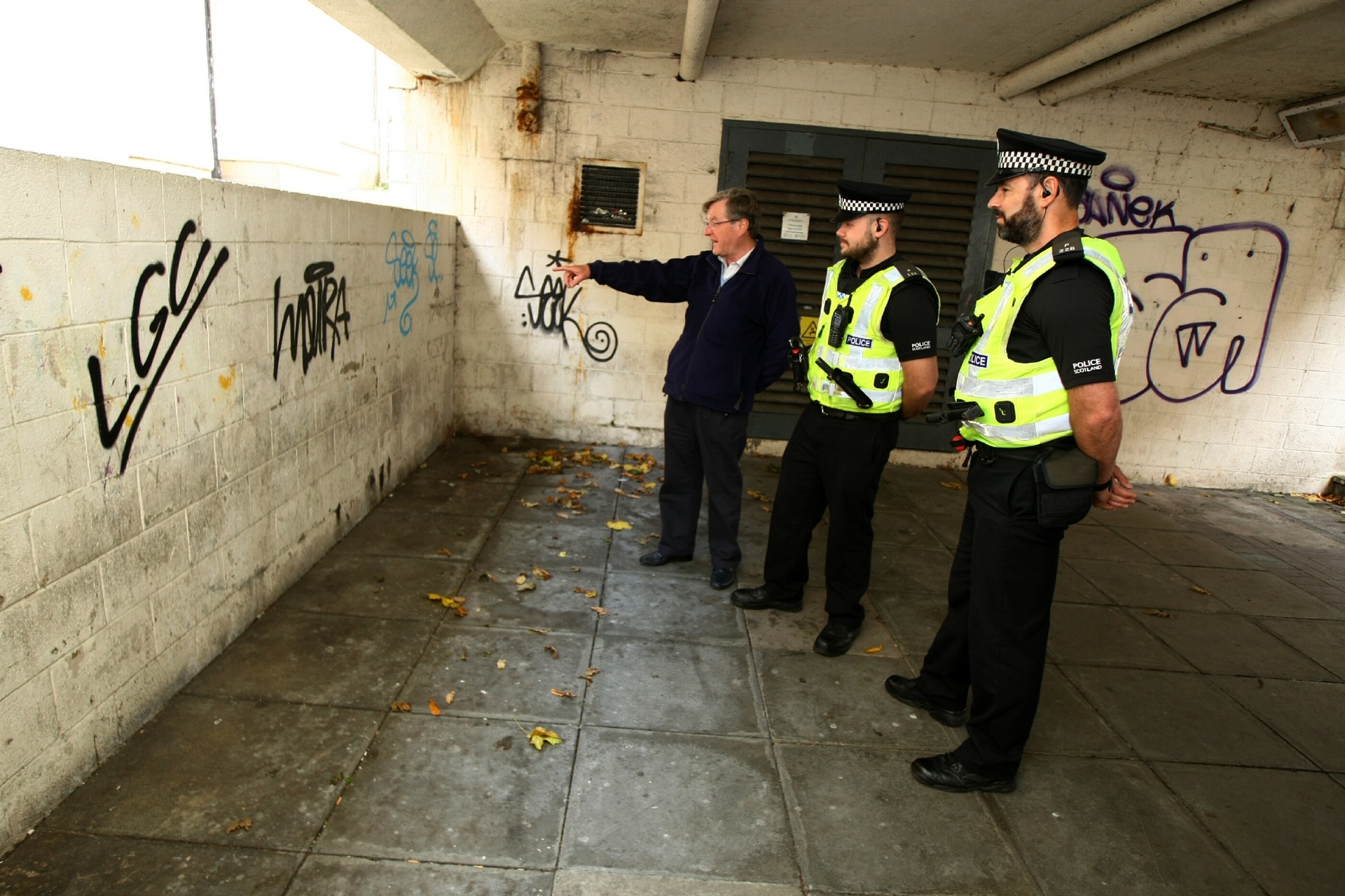 L-R: David Henderson - Chairman of Kirkcaldy West Community Council, Constable Cameron Lee and Constable Mark McCulloch, beside some of the graffiti at the back of the Postings in Kirkcaldy.