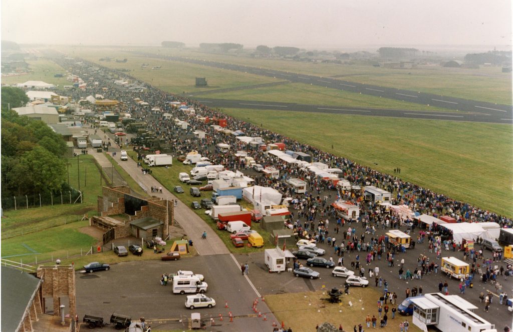 Crowds around the stalls at the RAF Leuchars airshow with static aircraft in the distance.  19 September 1992.