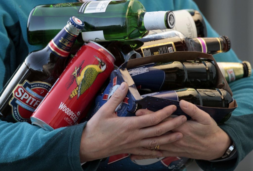 someone holding an armful of bottles and cans of beer and cider