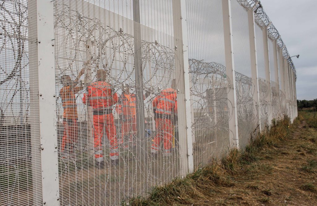 Workers fix the fence next to the refugee camp named "jungle"on September 19, 2016 in Calais, France. 
