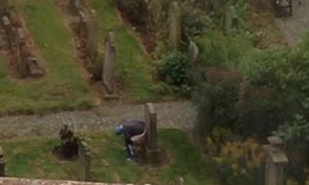 A man using the headstone as a toilet.