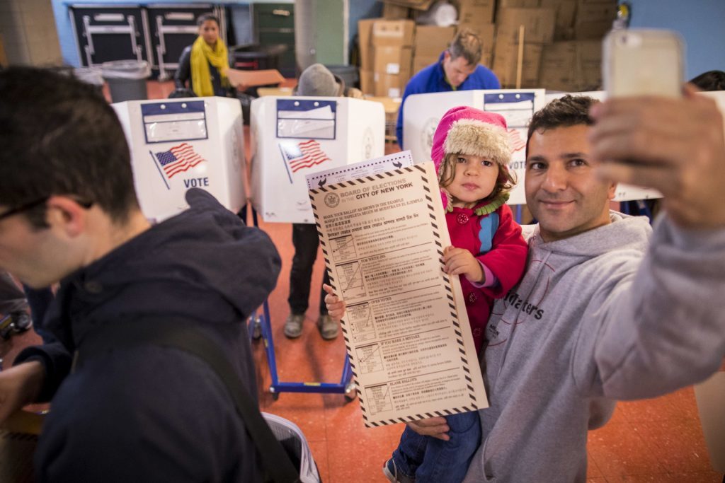 A man takes a selfie with his child as he waits to vote at a polling station in the Brooklyn borough of New York