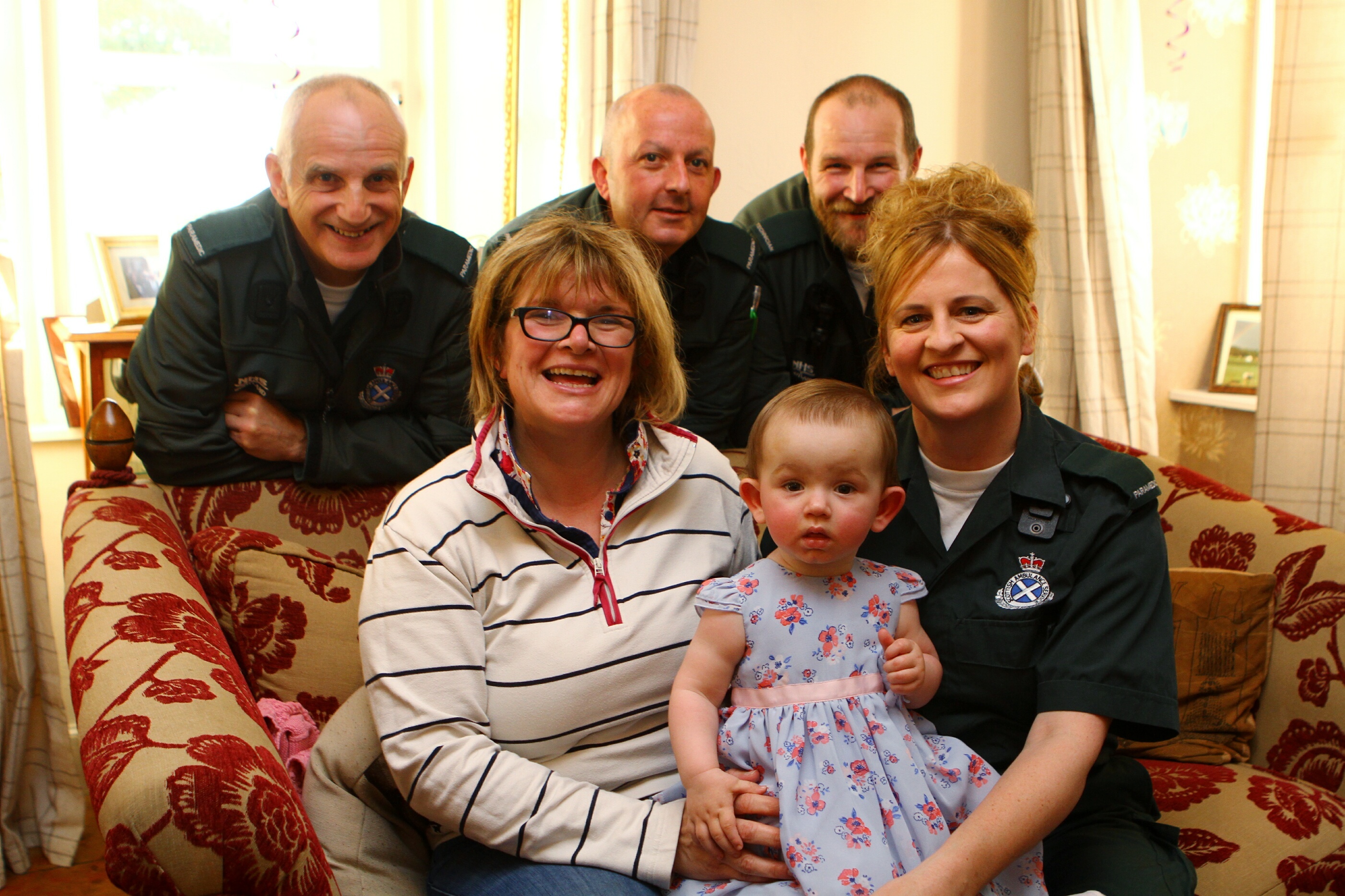 Baby Darcy Fleming celebrating her first birthday at Peel Farm with mum Claire and Paramedics Angie McKenzie, and back L/R, Stuart Parker, Stuart Wilkie,  and Steven Dryden.