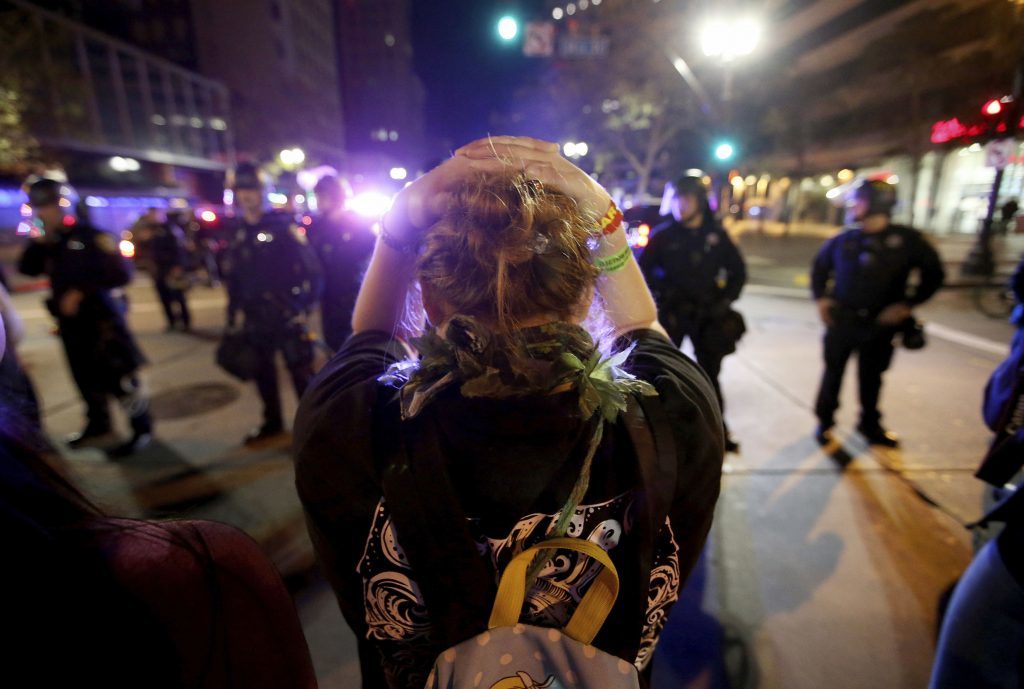 A protester faces a police line in downtown Oakland, California