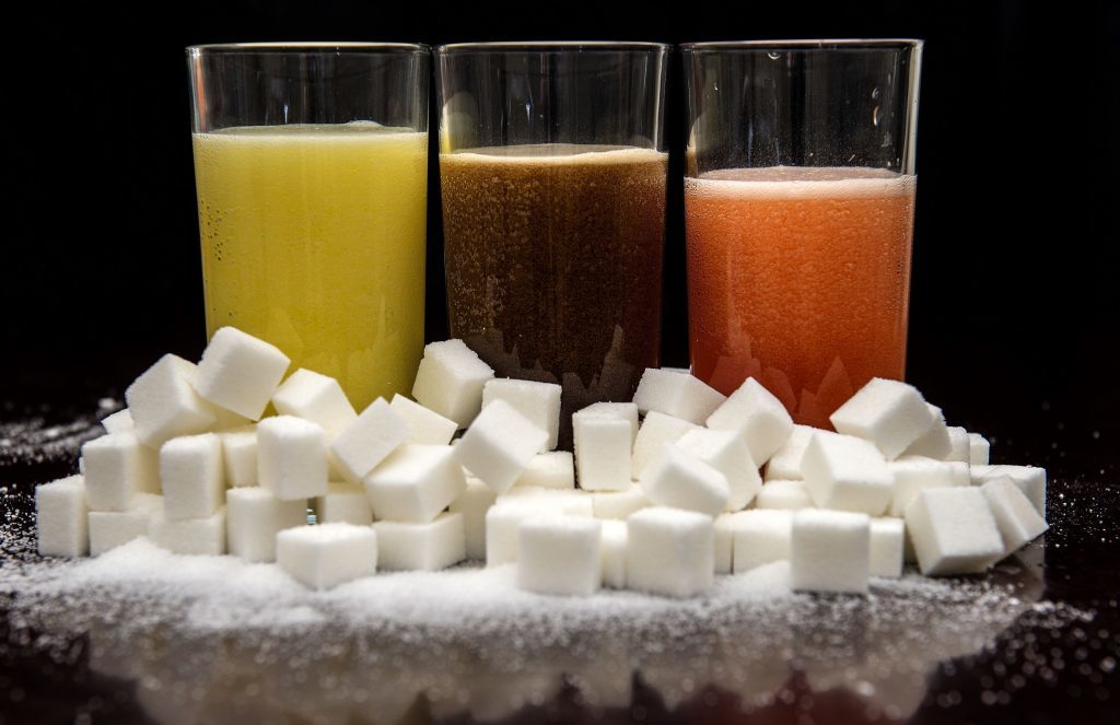 Carbonated drinks surrounded by sugar cubes,