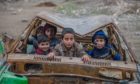 Syrian kids pose for a photograph inside a wreckage of a car in 2016