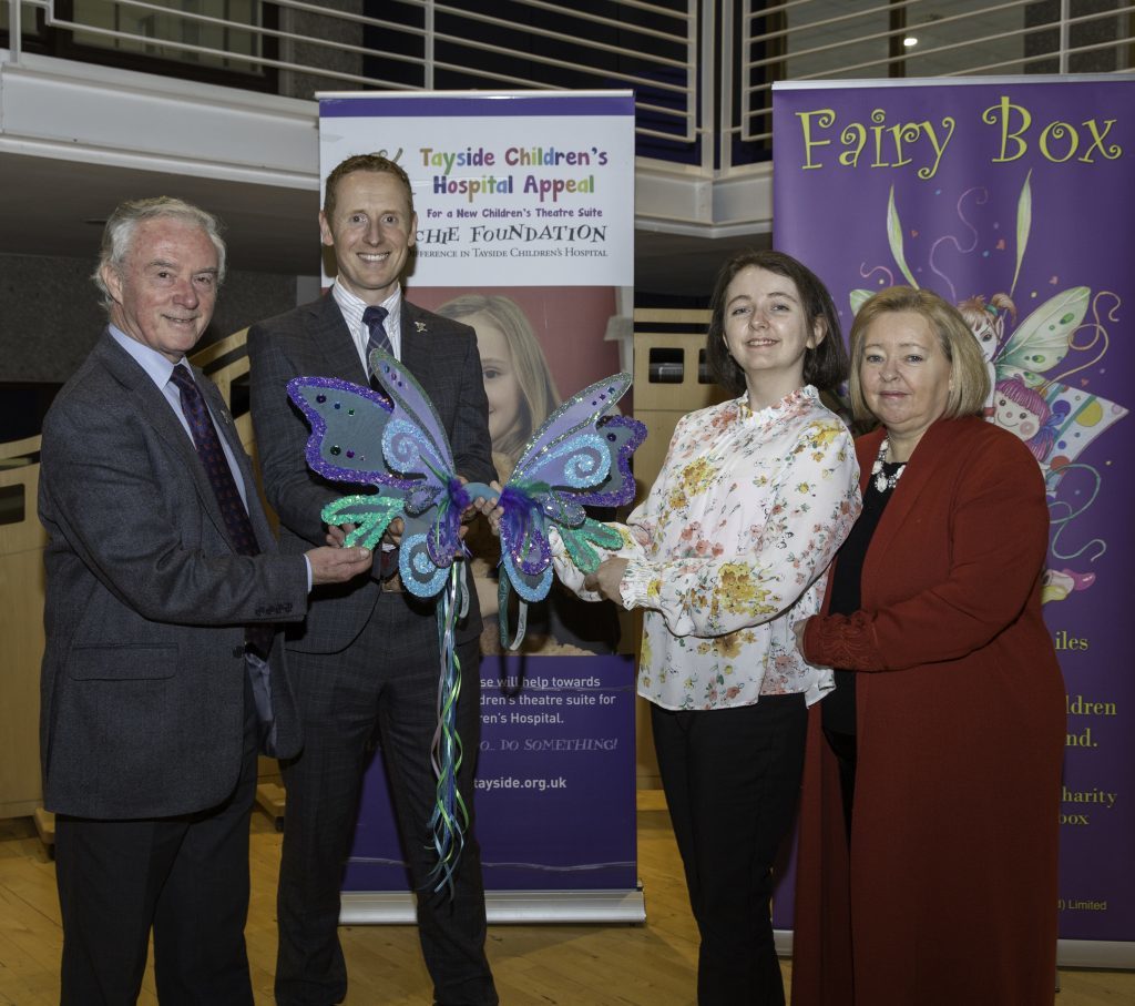 L-R Joe Mackie, chairman, and David Cunningham, chief executive of The ARCHIE Foundation accept the fairy wings from Aimee and Rosemary Butler