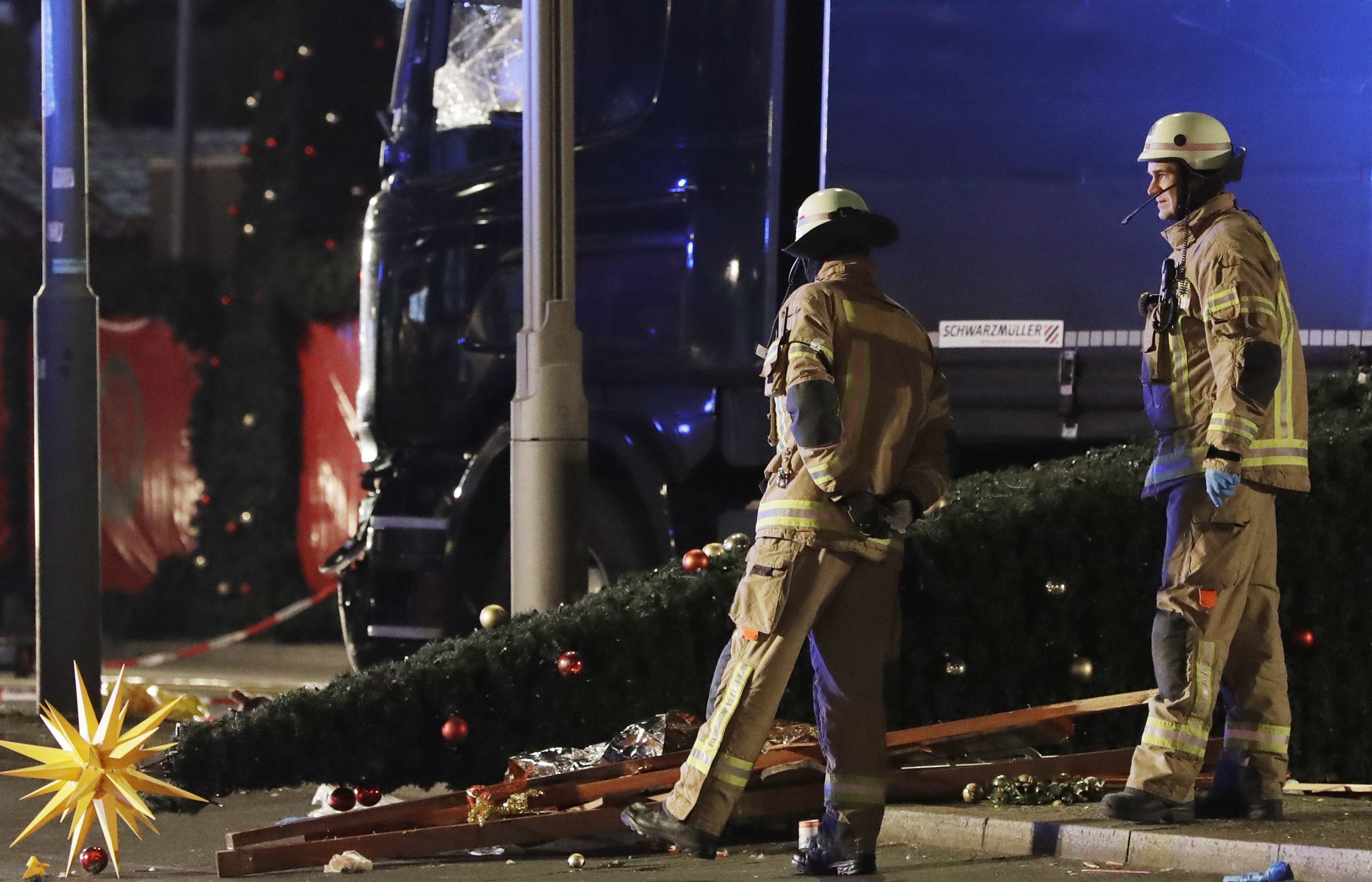 Emergency workers examine the lorry and a Christmas tree toppled by the impact.