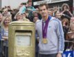 Andy murray stands next to his gold painted post box in Dunblane.
