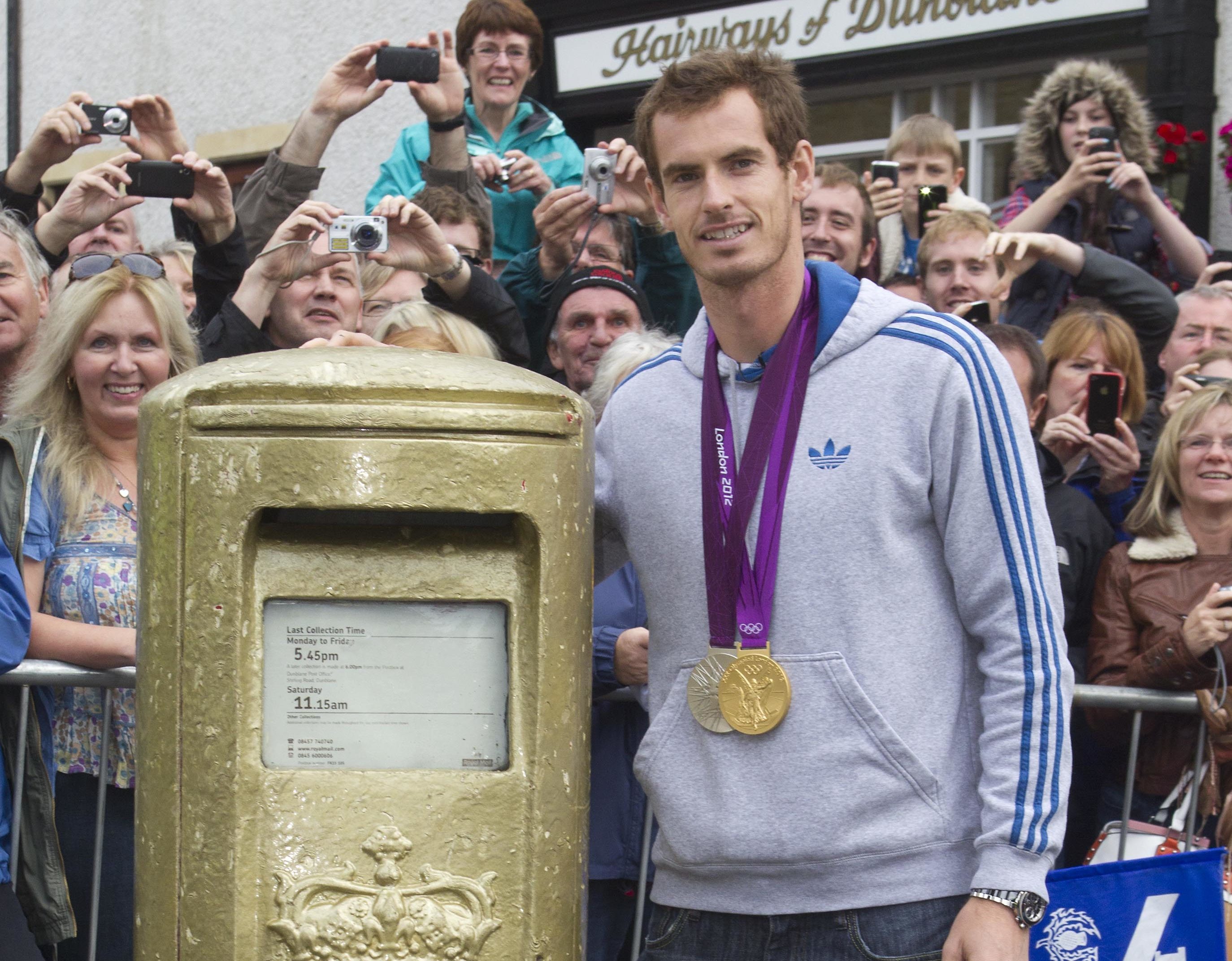Andy murray stands next to his gold painted post box in Dunblane.
