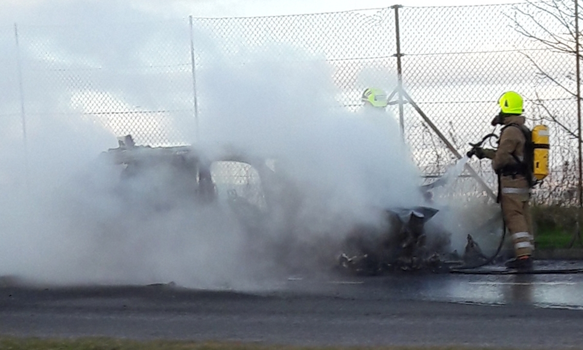 Firefighters tackle the blazing vehicle.