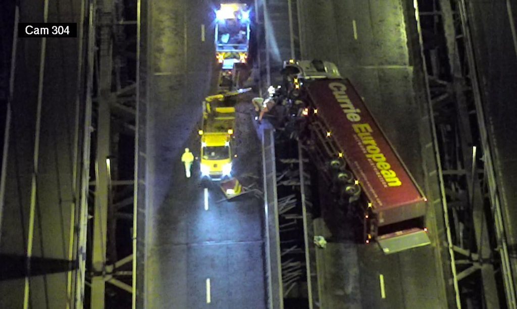 An overhead camera shows the toppled lorry.