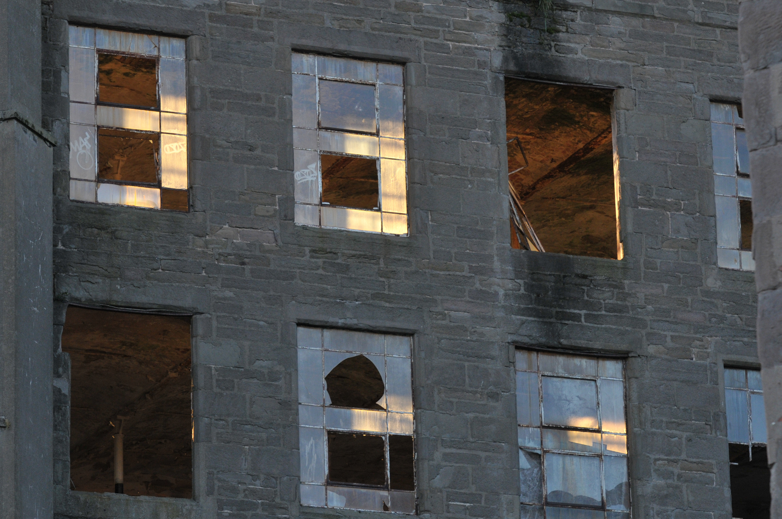 The setting sun lights a window in one of the old disused mill buildings on the Cowgate in Dundee