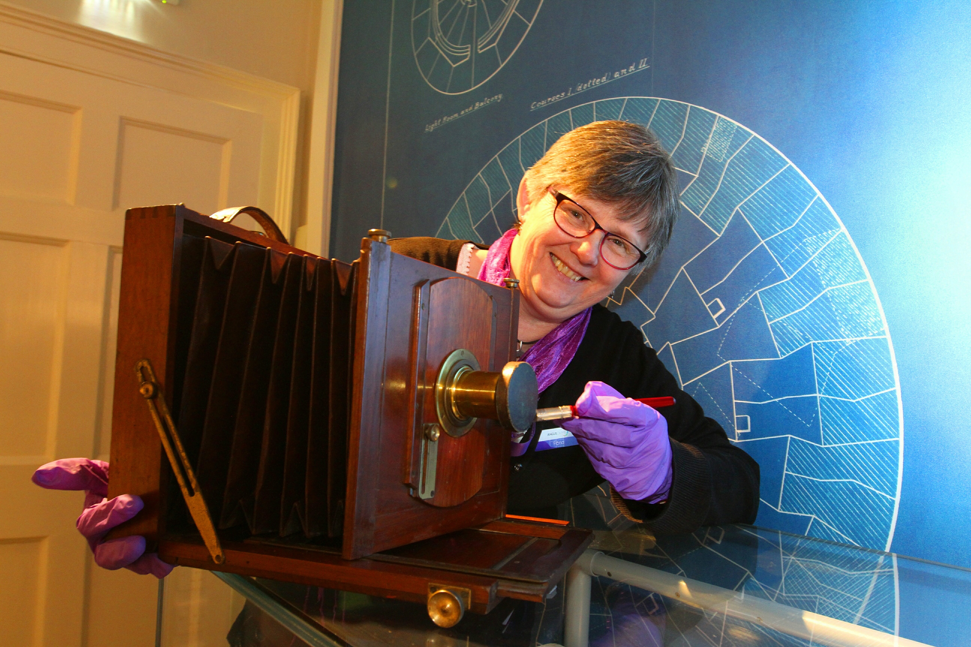 Senior archivist Fiona Scharlau cleans a half plate folding camera, dated 1850.