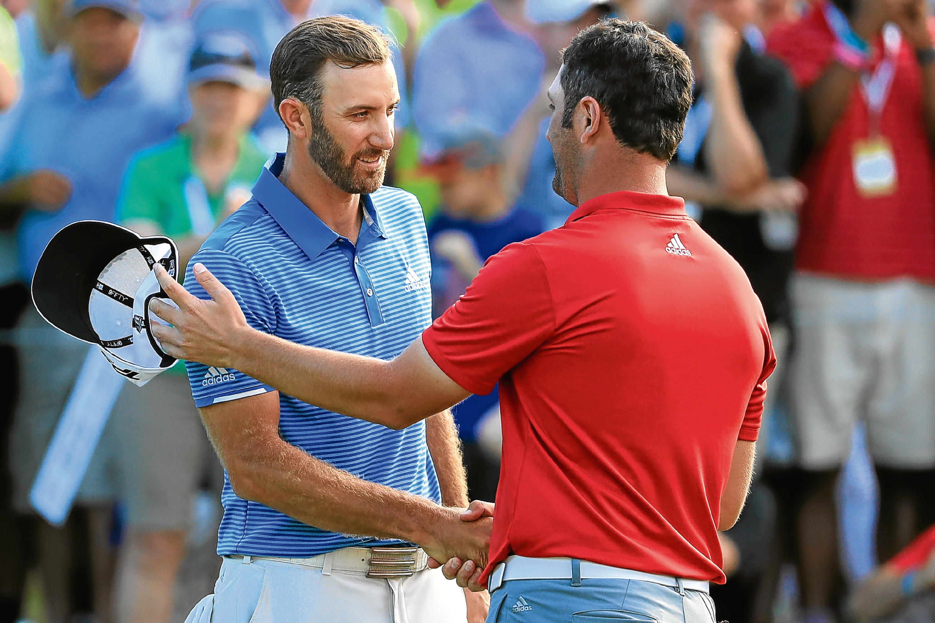 Dustin Johnson shakes hands with Jon Rahm of Spain.