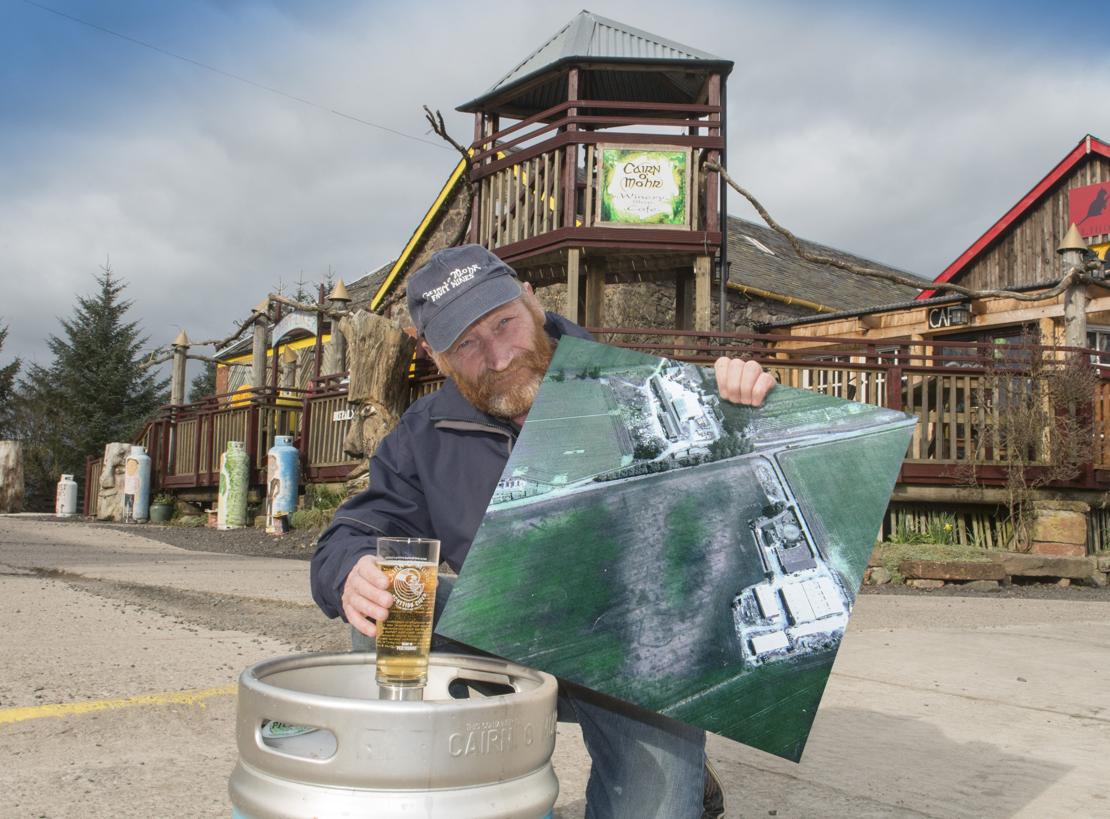 Ron Gillies, winery owner, pictured with the new draught cider and the aerial photograph showing the outline of the prehistory Pictish settlement.