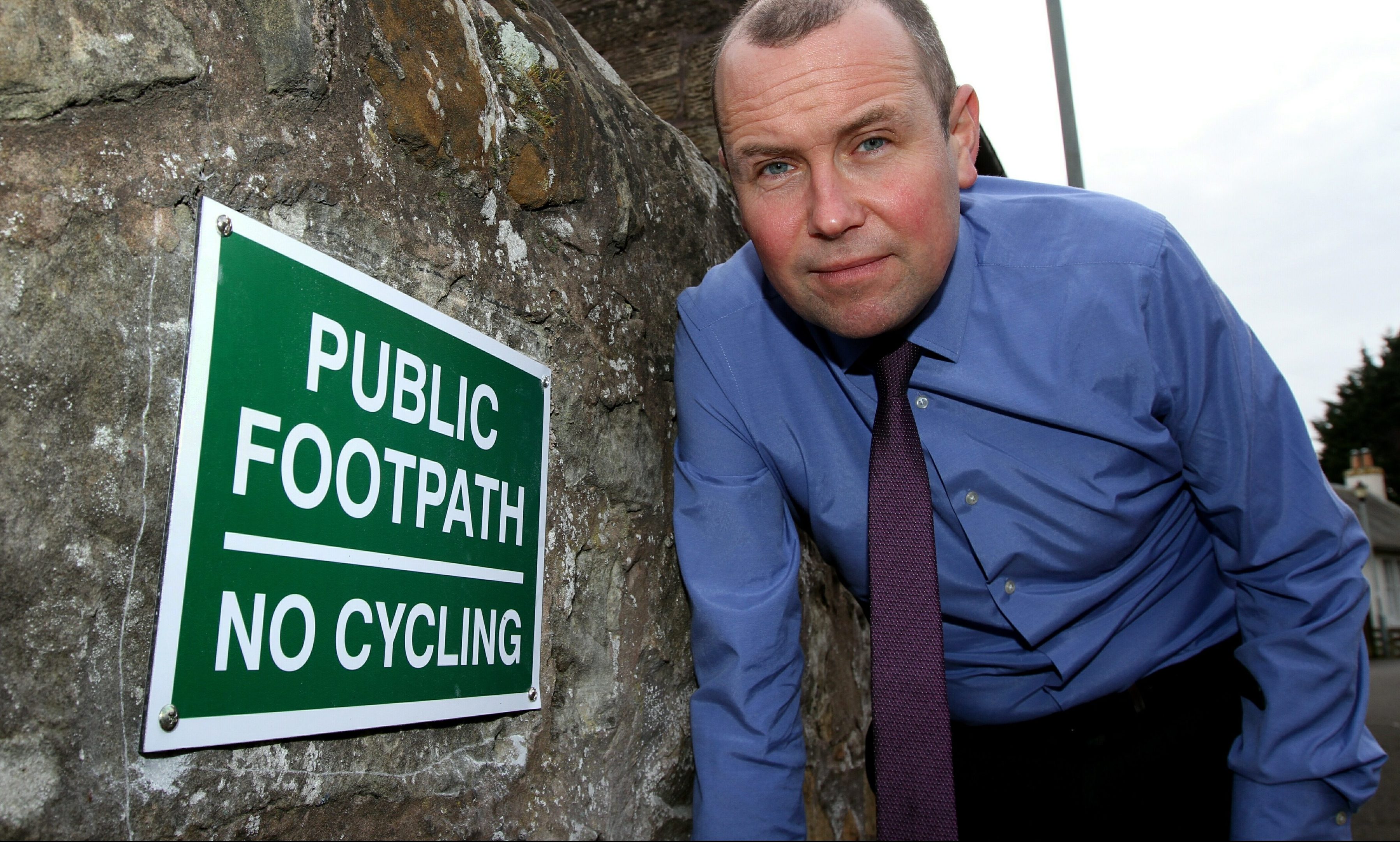 Brian Thomson beside the unauthorised sign.