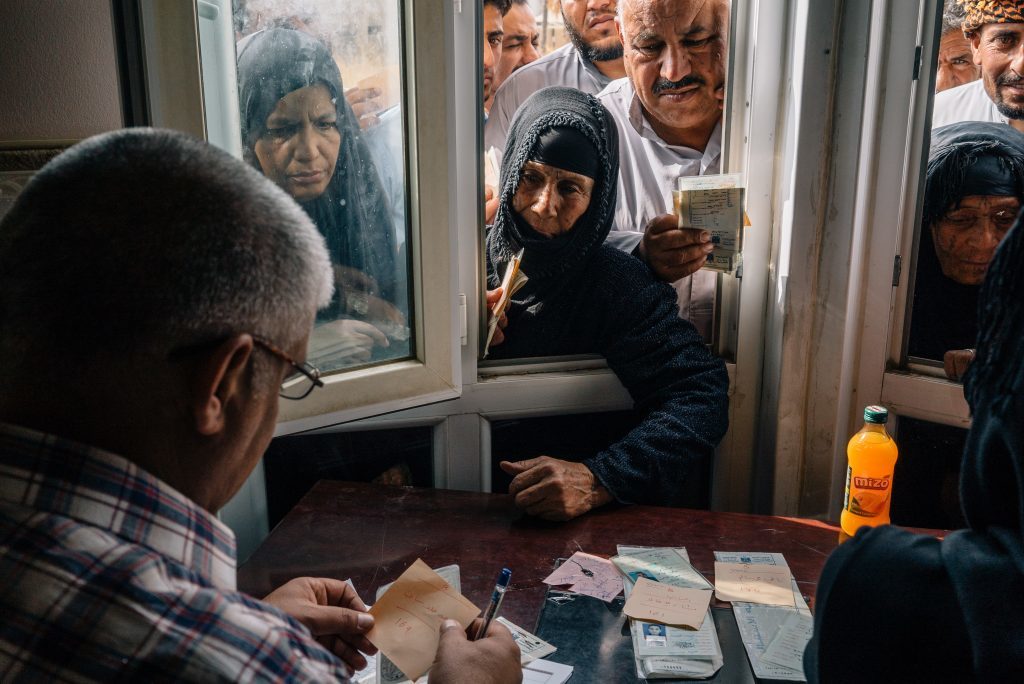 Displaced persons in Iraq reach through a window of a distribution centre where cash donations are made. Each registered civilian displaced by conflict receives a donation of 400USD. 