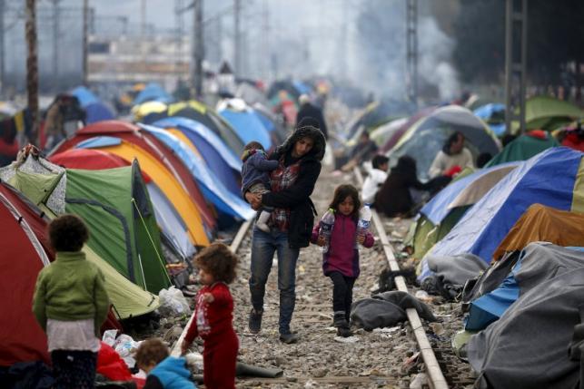 Migrants walk on a railway track at a makeshift camp on the Greek-Macedonian border, near the village of Idomeni, Greece March 12, 2016. 