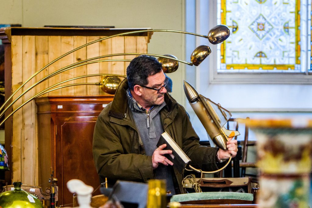 A man inspects an unusual looking lamp.