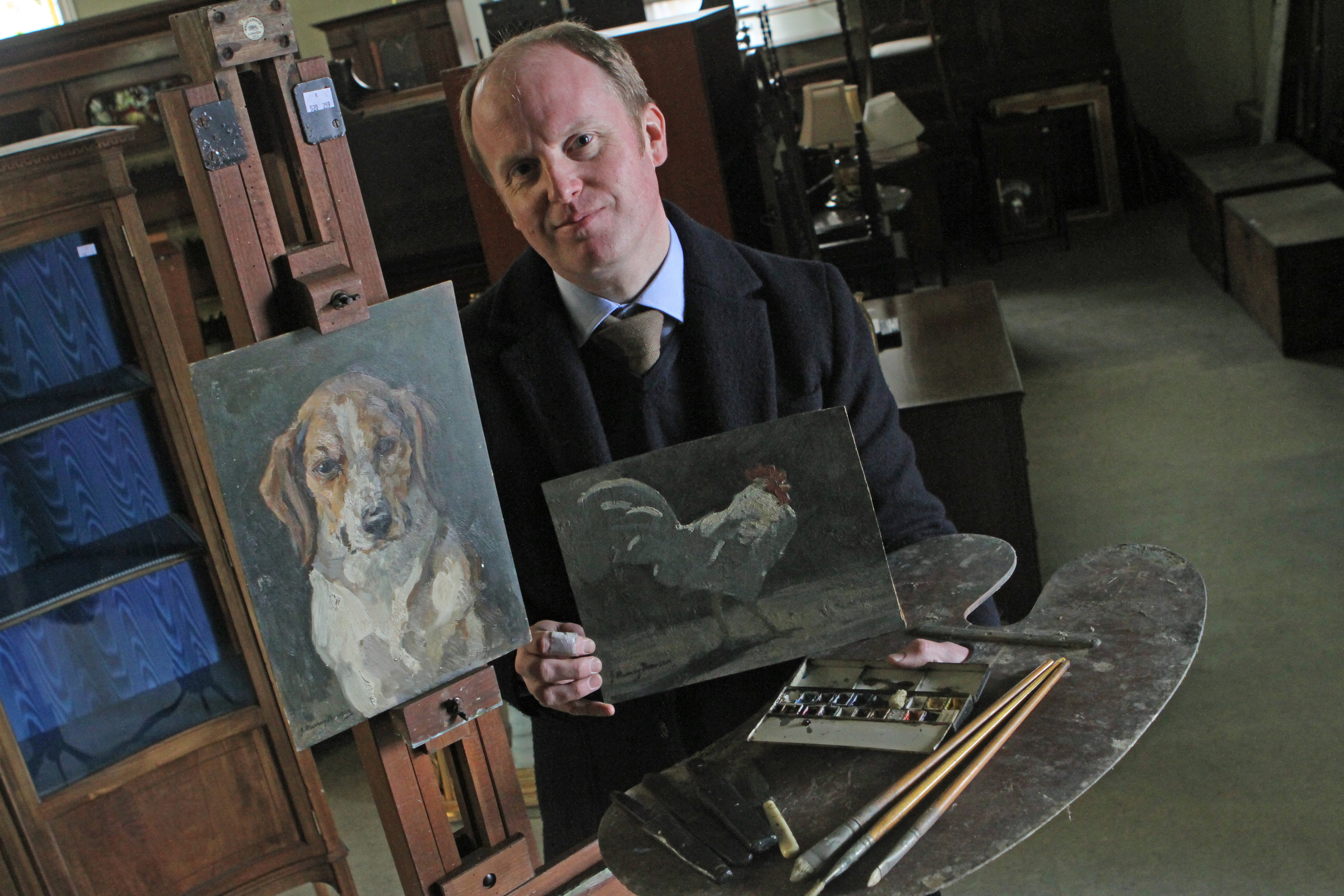 Auctioneer Nick Burns with some of the artist's work and equipment.