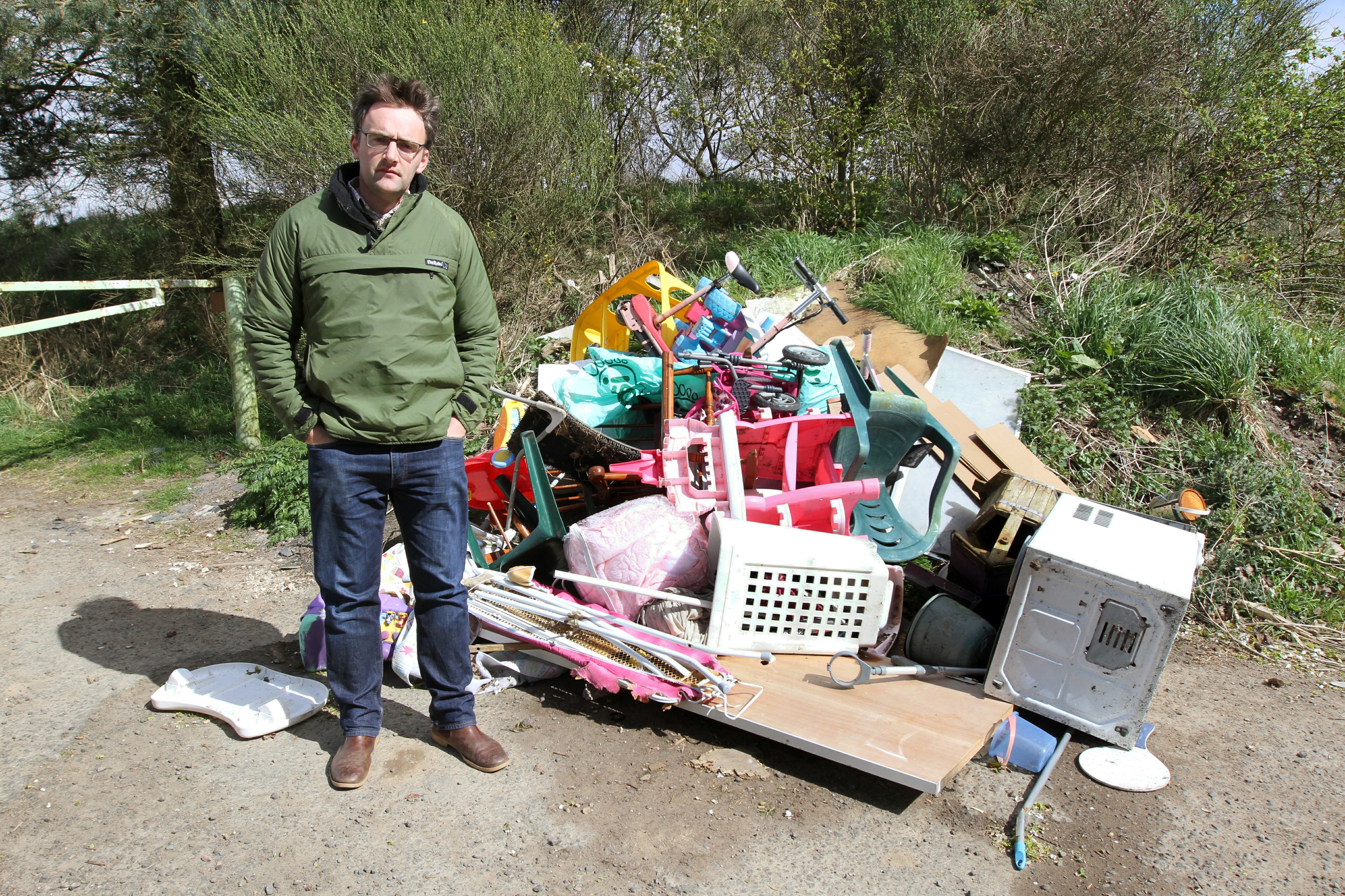 Tom Pate beside the rubbish dumped on Emmock Road.