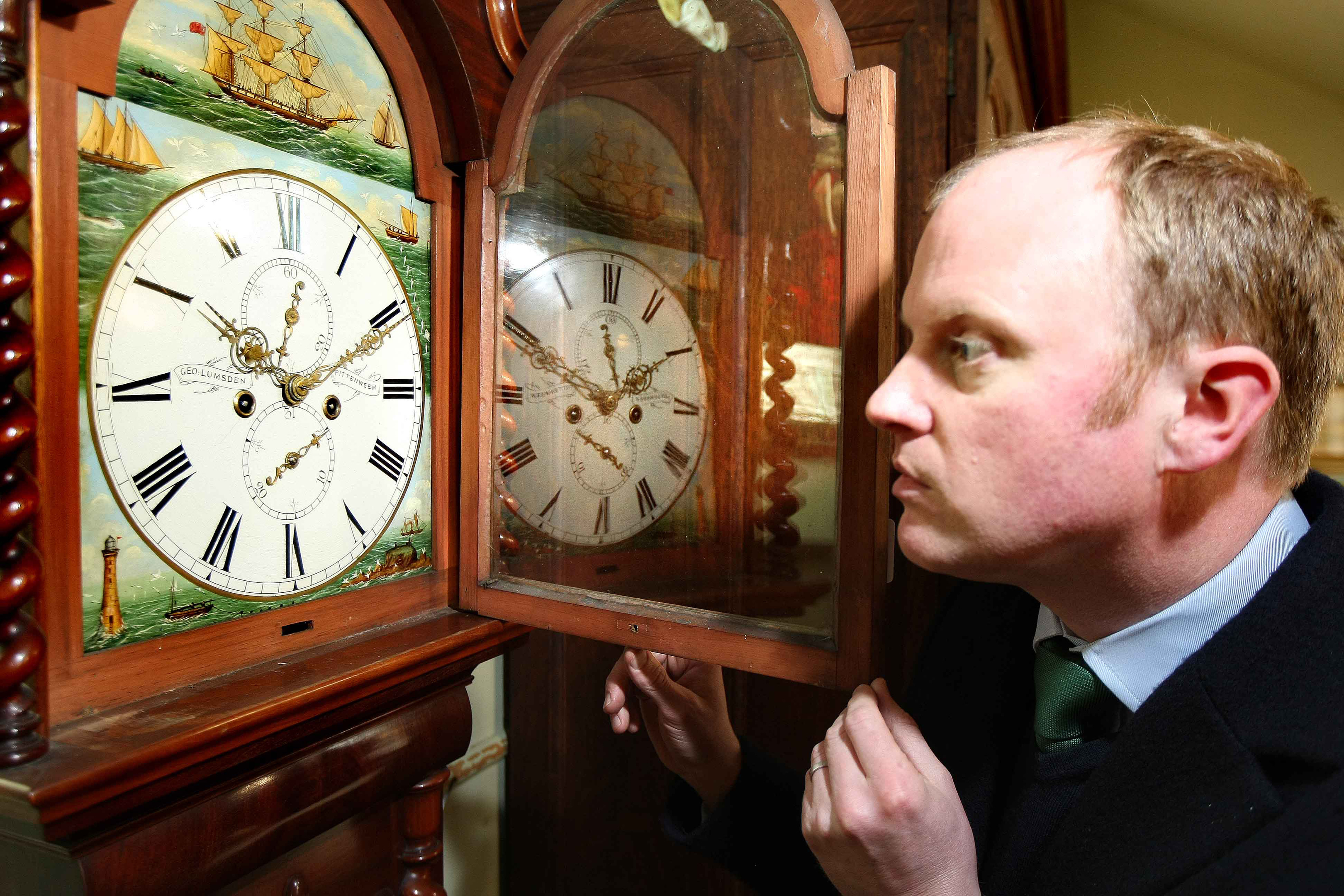 Auctioneer Nick Burns admires the detail on the George Lumsden of Pittenweem clock.