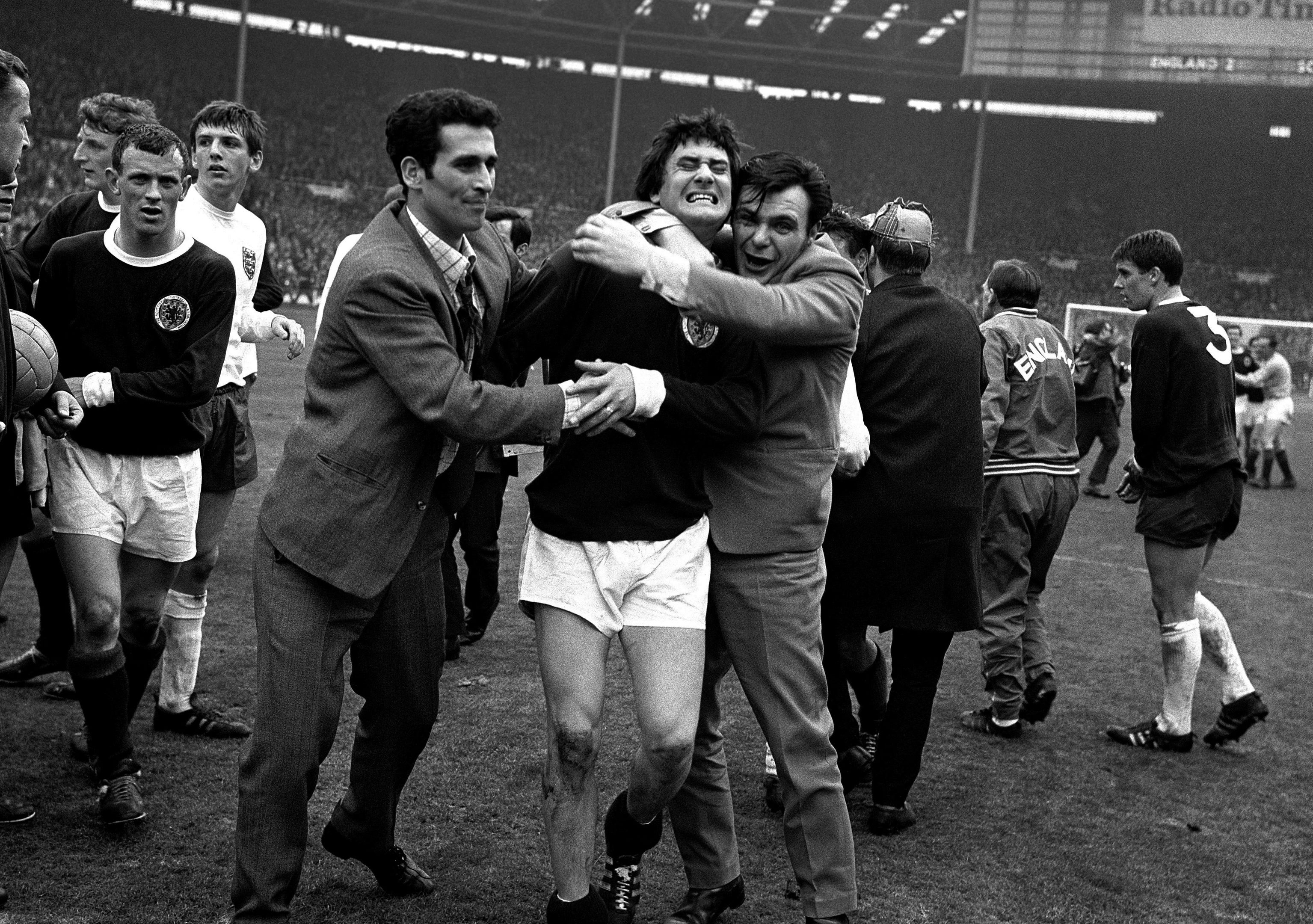 The squeeze makes itself felt for Scotland's Jim Baxter (centre), enthusiastically hugged by overjoyed fans who invaded the Wembley Stadium pitch after England had been beaten 3-2 in their football match against Scotland on April 15, 1967