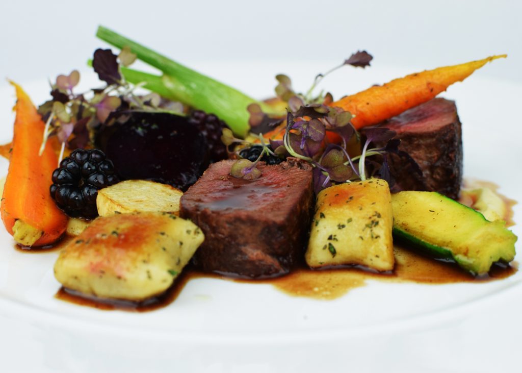 Venison loin with rosemary gnocchi, roast baby vegetables and blackberry jus.