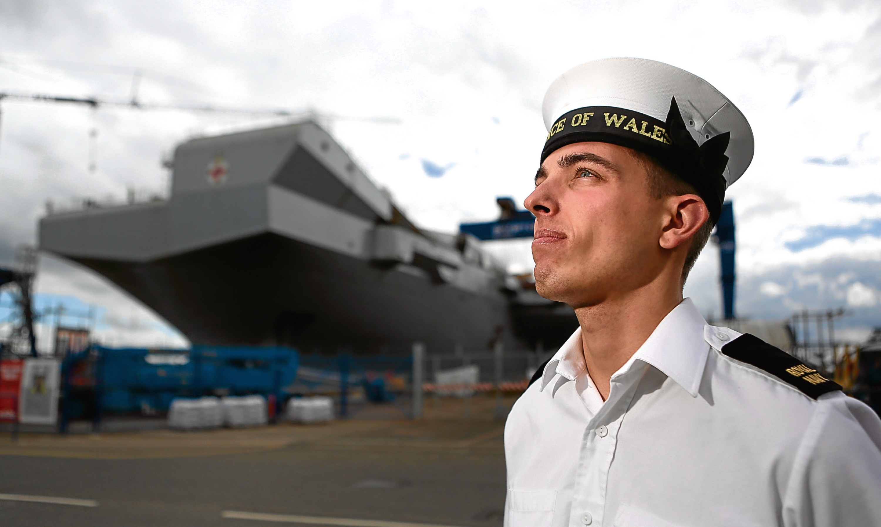 Courier News - PrinceCharles - Aircraft Carrier - Babcock - Rosyth. Prince Charles visiting aircraft carrier named after himself. Which will be nice. Hell be touring the ship, meeting dockyard workers before striking a gavel that places the final piece in to the flight deck. Picture shows; AB Iain Harris in HMS Prince of Wales cap in front of the ship, Monday 20 June 2016.