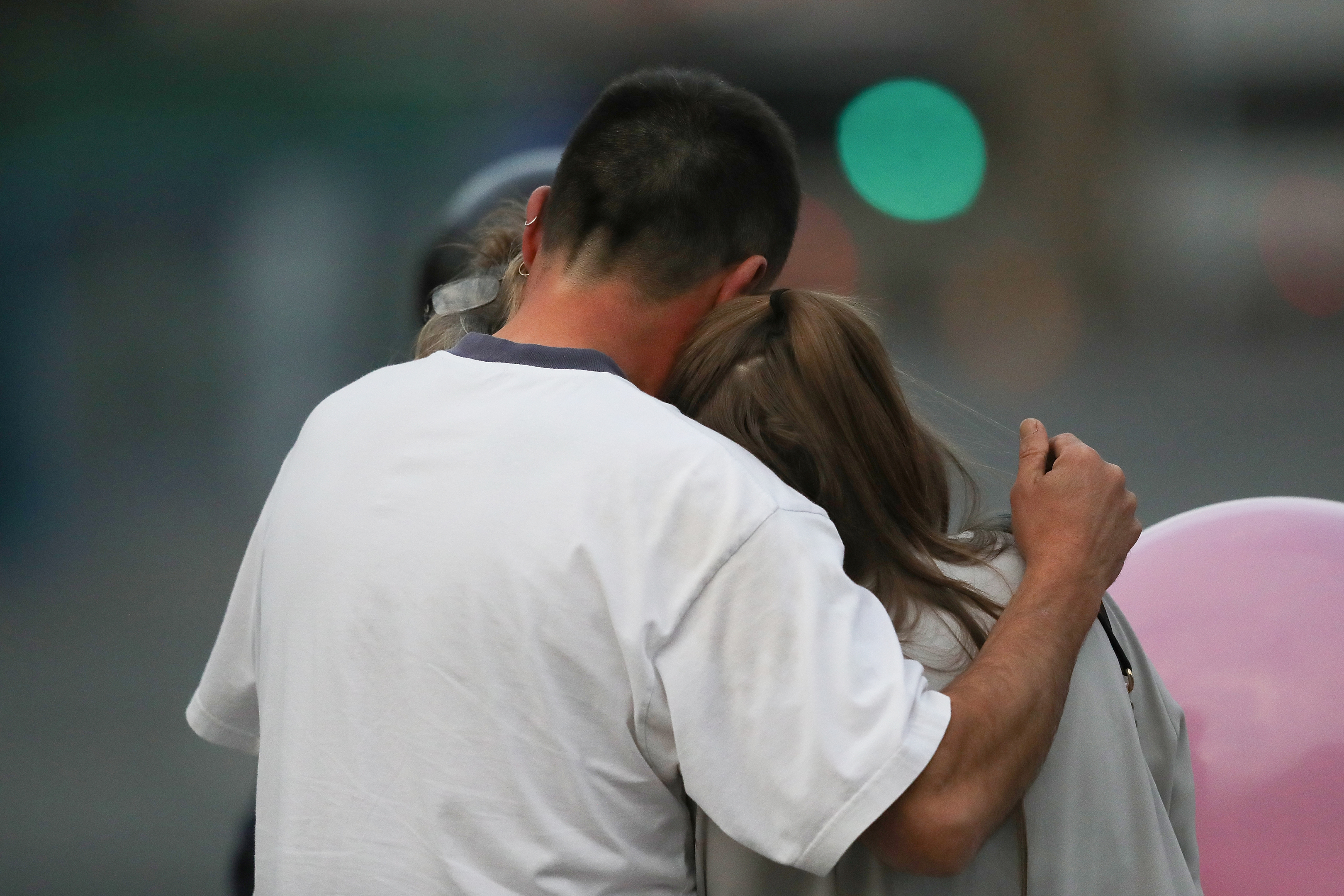 A man embraces a woman and a teenager as he collects them from the Park Inn Hotel where they were given refuge after last night's explosion at the Manchester Arena.