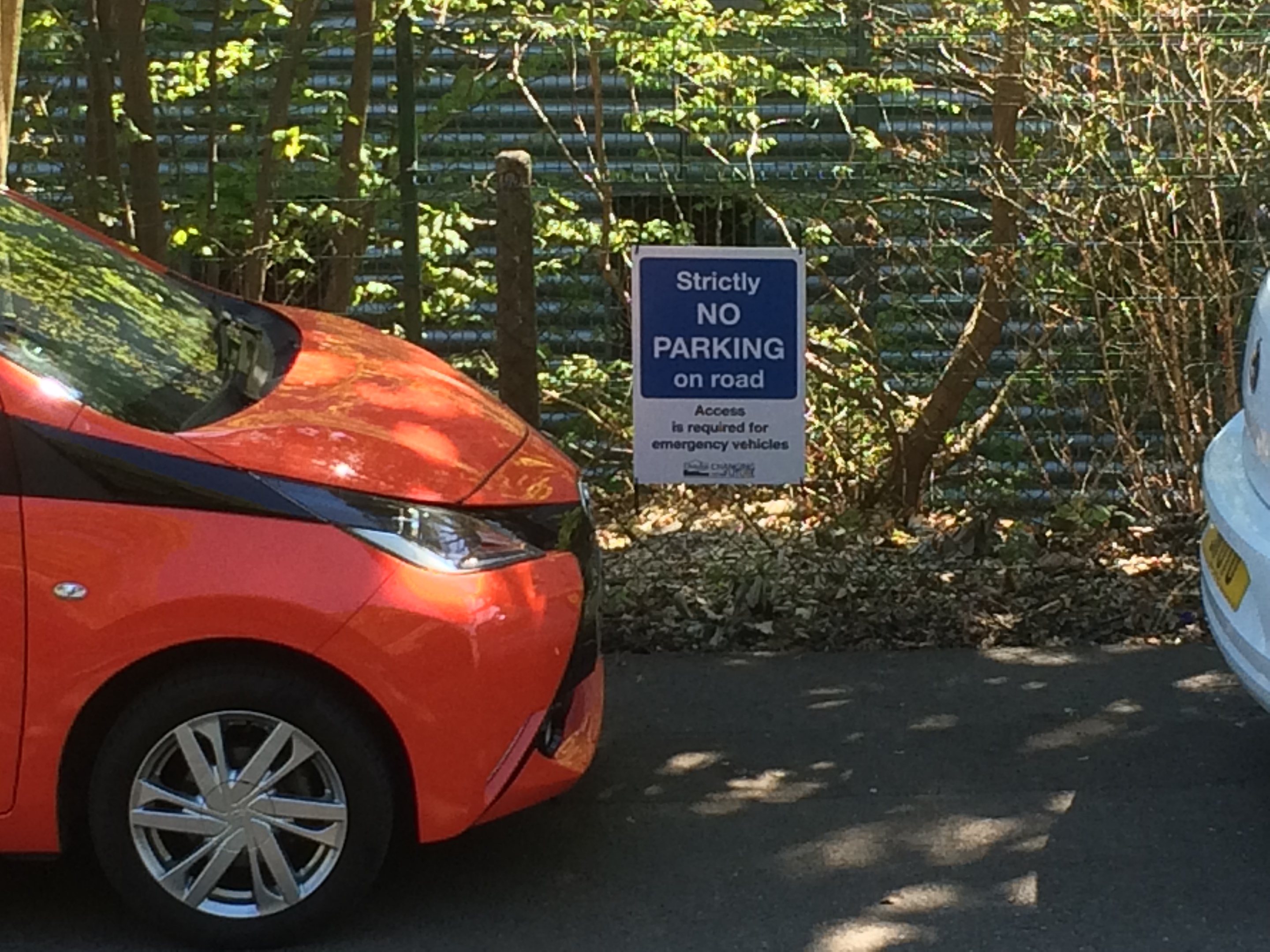 A car parked on the road, in front of the council sign.