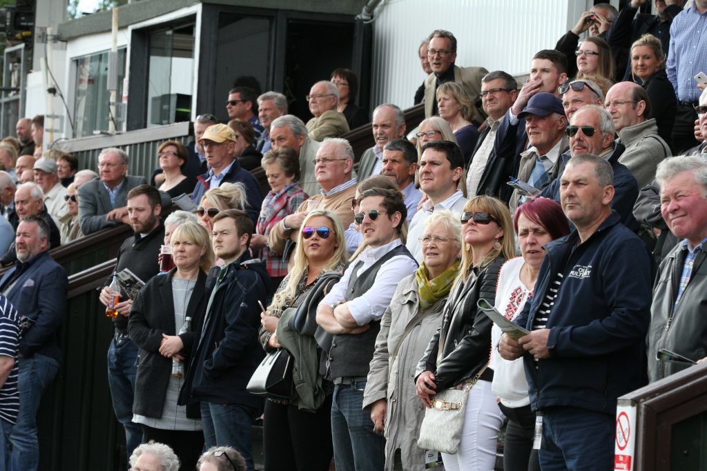 The crowd watch action from the first race which was won by "Just Before Dawn".