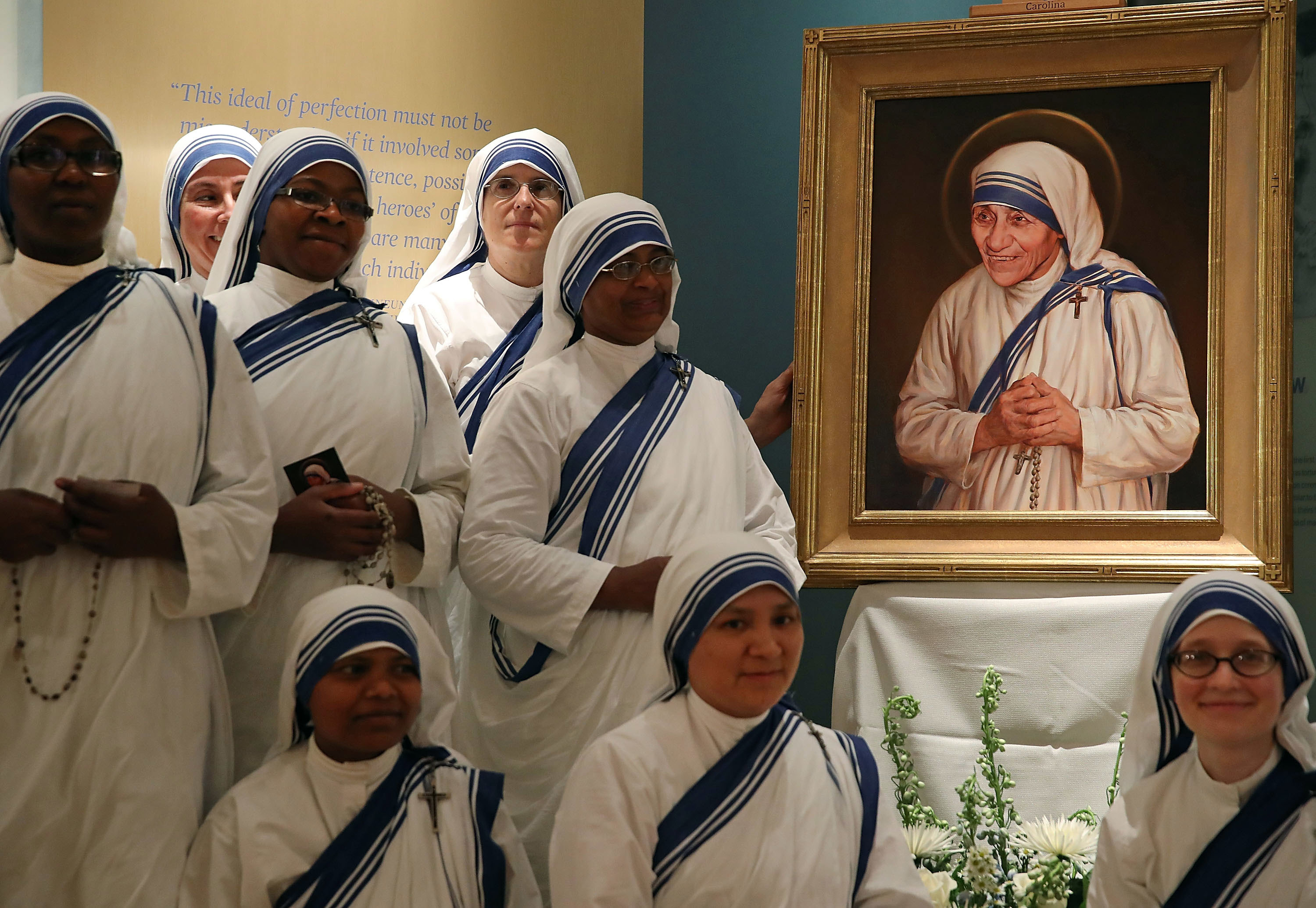 Sisters of the Missionaries of Charity stand in front of the official canonisation portrait of Mother Teresa.