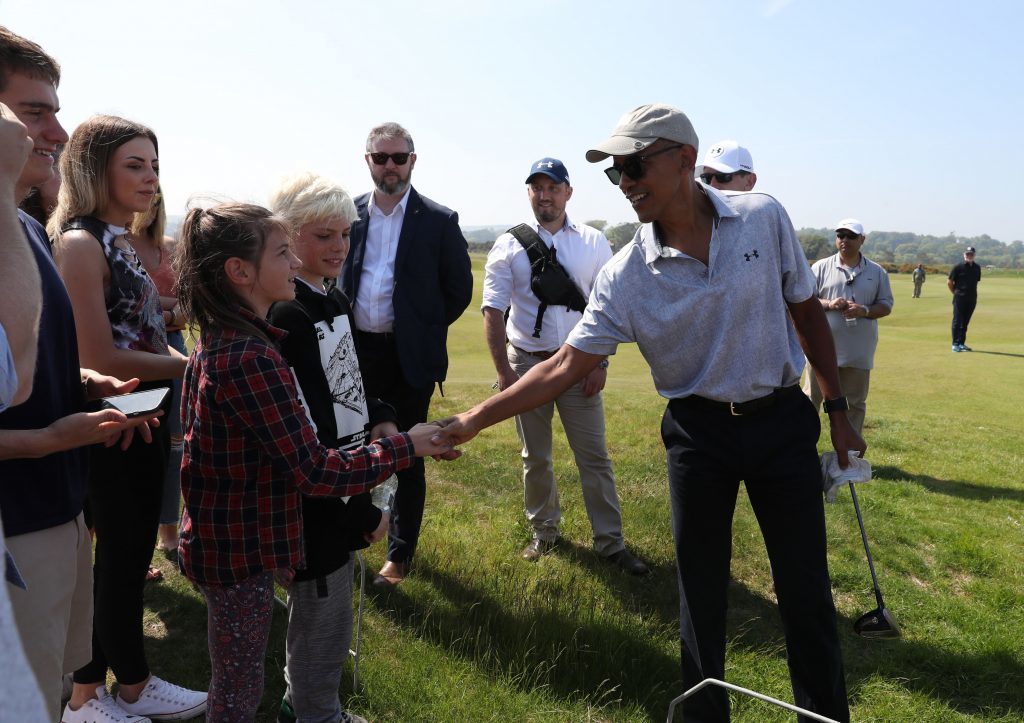 Former US president Barack Obama shakes hands with spectators as he plays a round of golf at St Andrews.