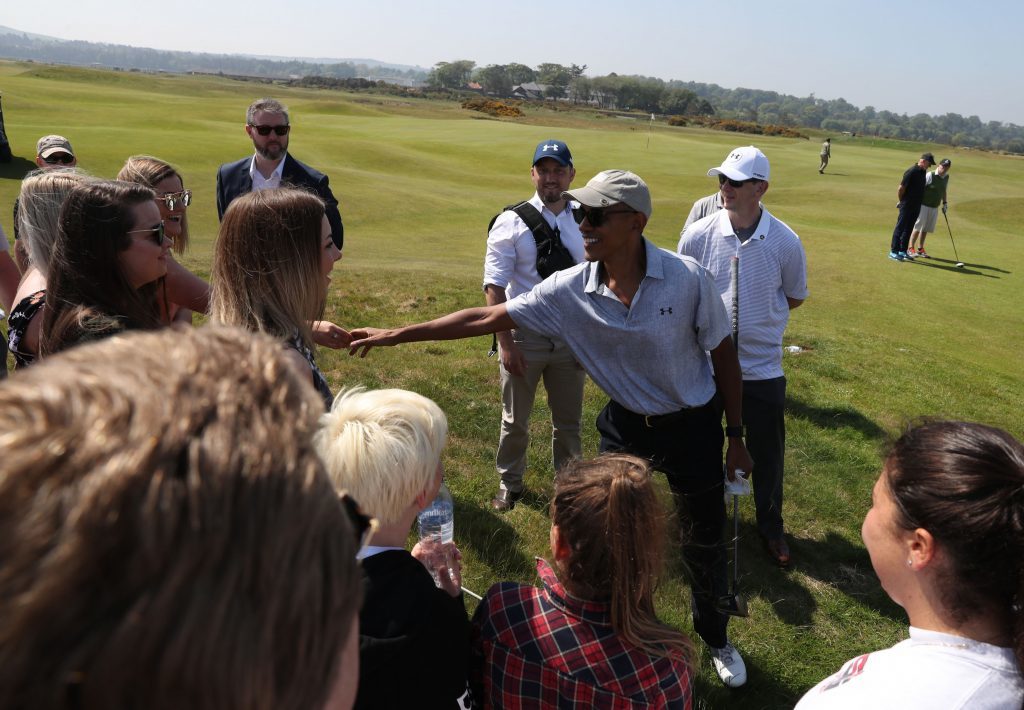 Former US president Barack Obama shakes hands with spectators as he plays a round of golf at St Andrews.