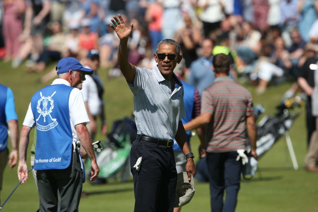 Former US president Barack Obama waves to spectators during a round of golf at St Andrews Old Course.