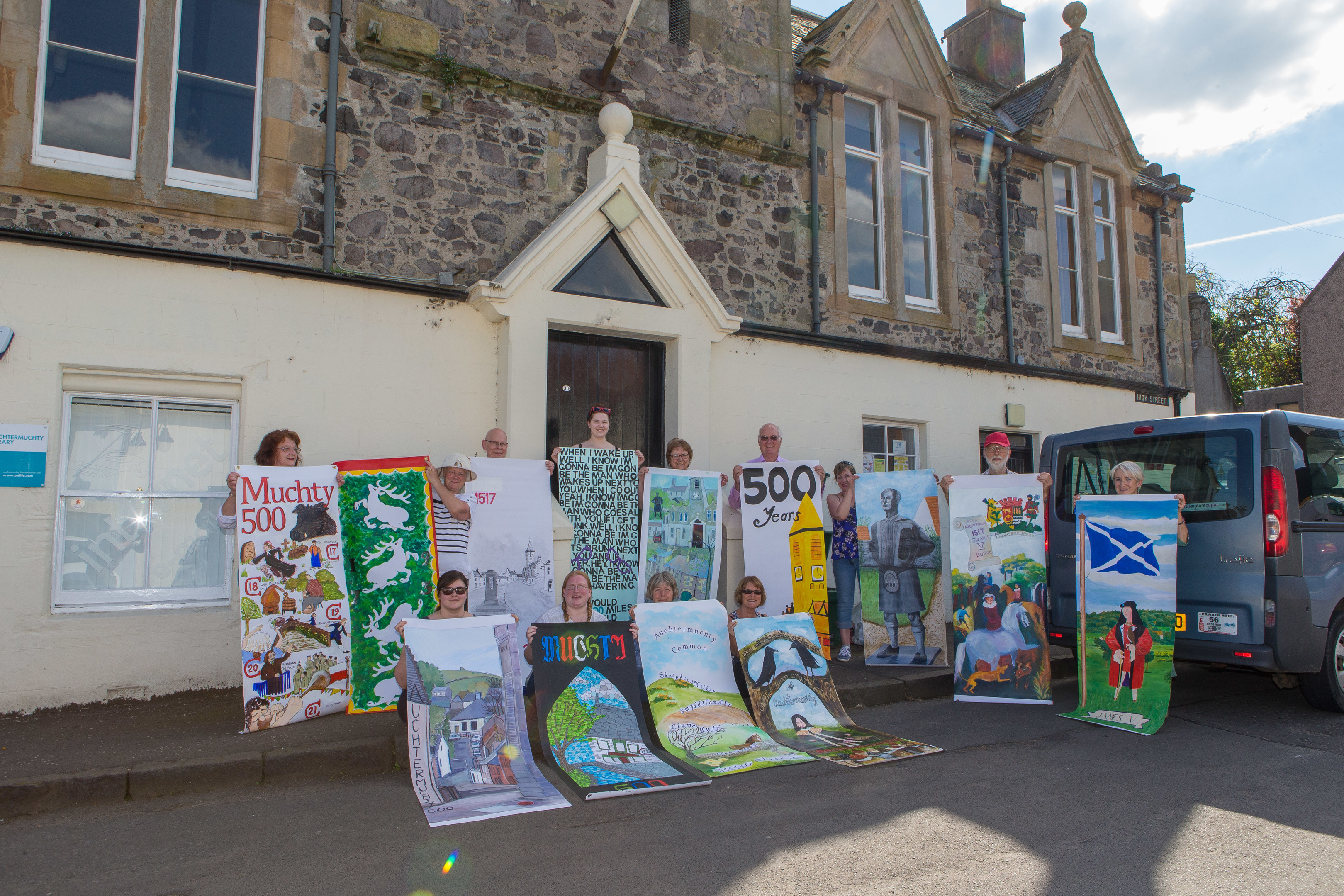 Members of the Muchty 500 group are hanging banners in the town square to advertise the upcoming shows in June.