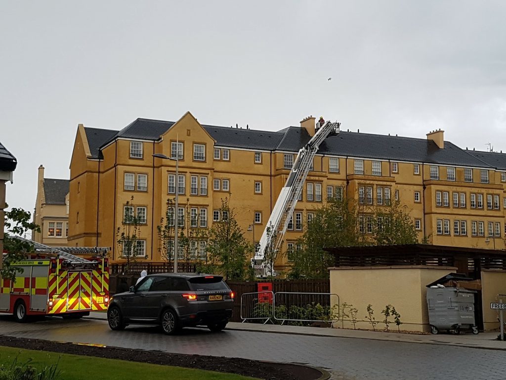 Firefighters check the roof of the flats at Abbey Park View in St Andrews after it was struck by lightning