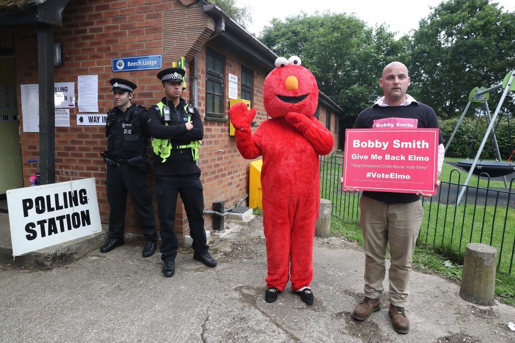 Candidate Bobby Smith arrives with Elmo as Police wait outside the polling station where Conservative Party leader Theresa May is expected to vote on 