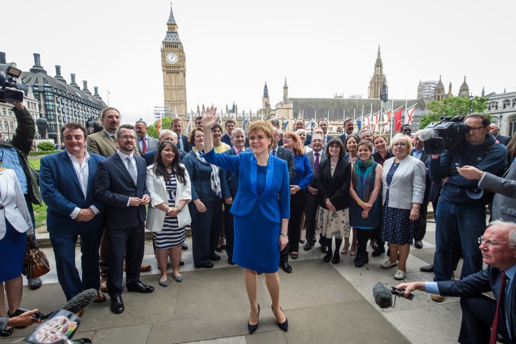 SNP leader Nicola Sturgeon waves in Parliament Square as she stands in front of SNP MPs elected in the general election.