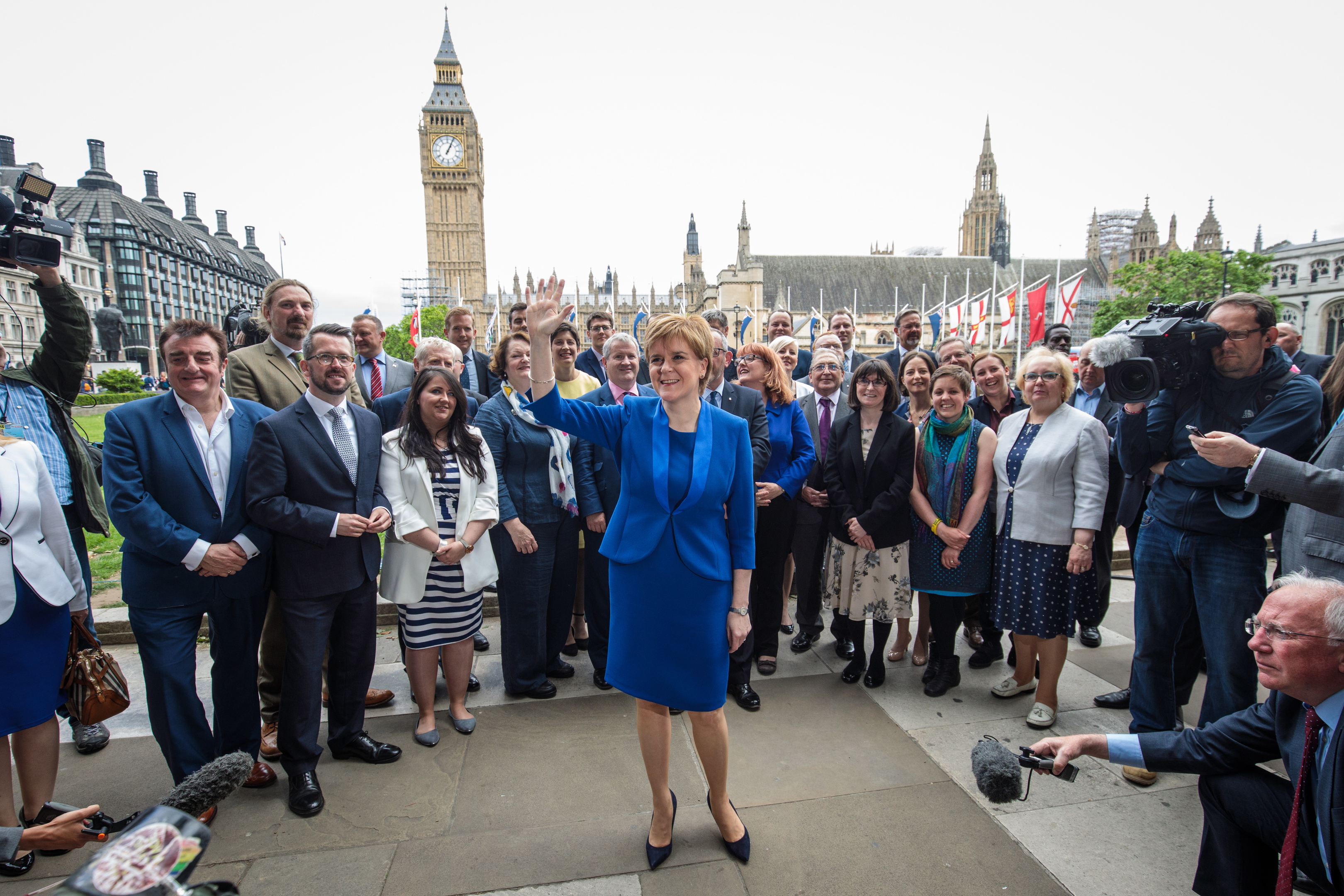 SNP leader Nicola Sturgeon waves in Parliament Square as she stands in front of SNP MPs elected in the general election.