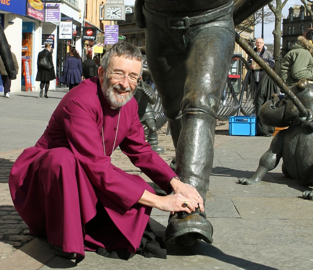 The Bishop Of Brechin Nigel Peyton shining the shoes of Desperate Dan in Dundee in 2012.