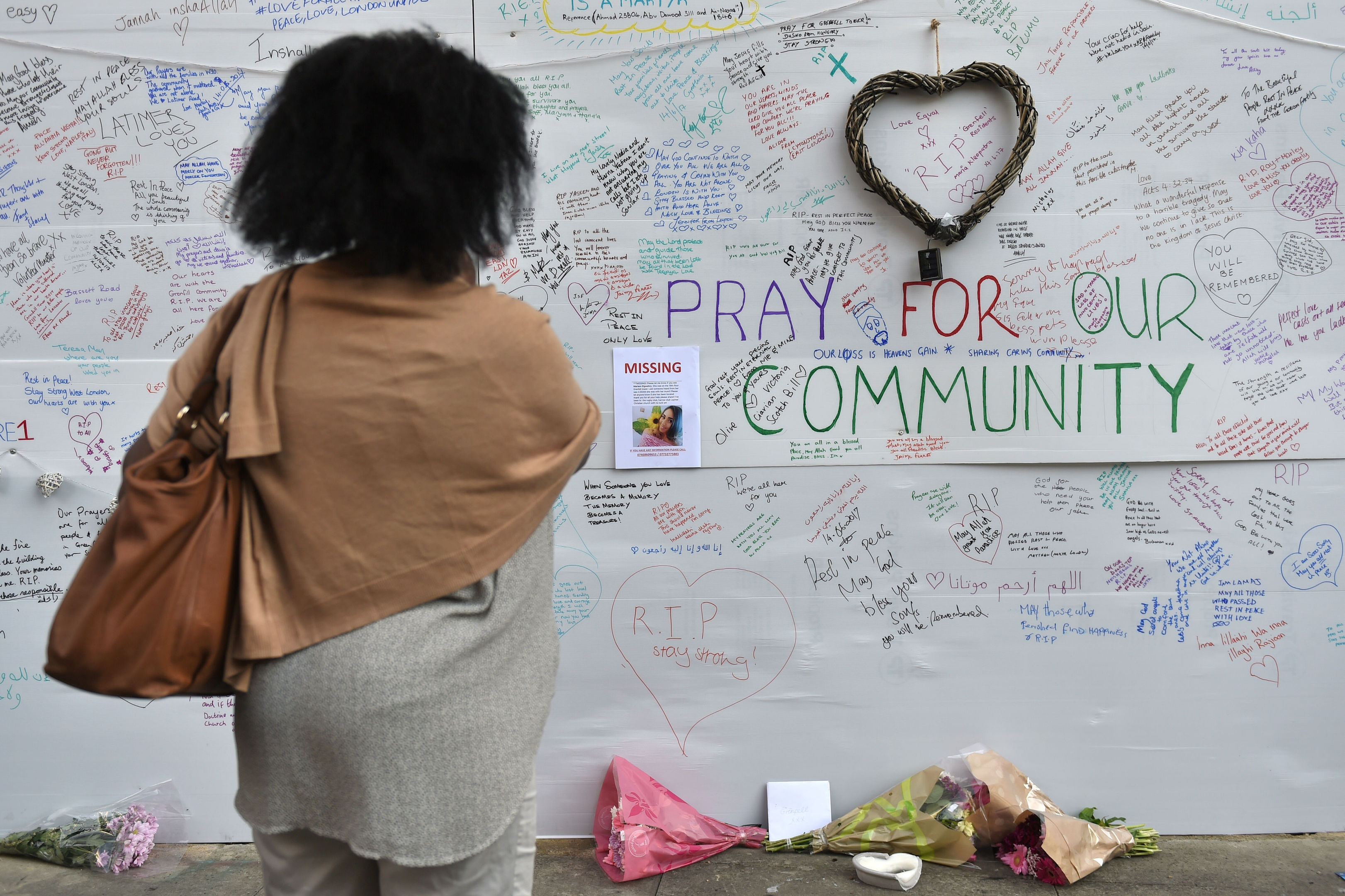 A woman reads a wall of tributes close to Grenfell Tower in west London.