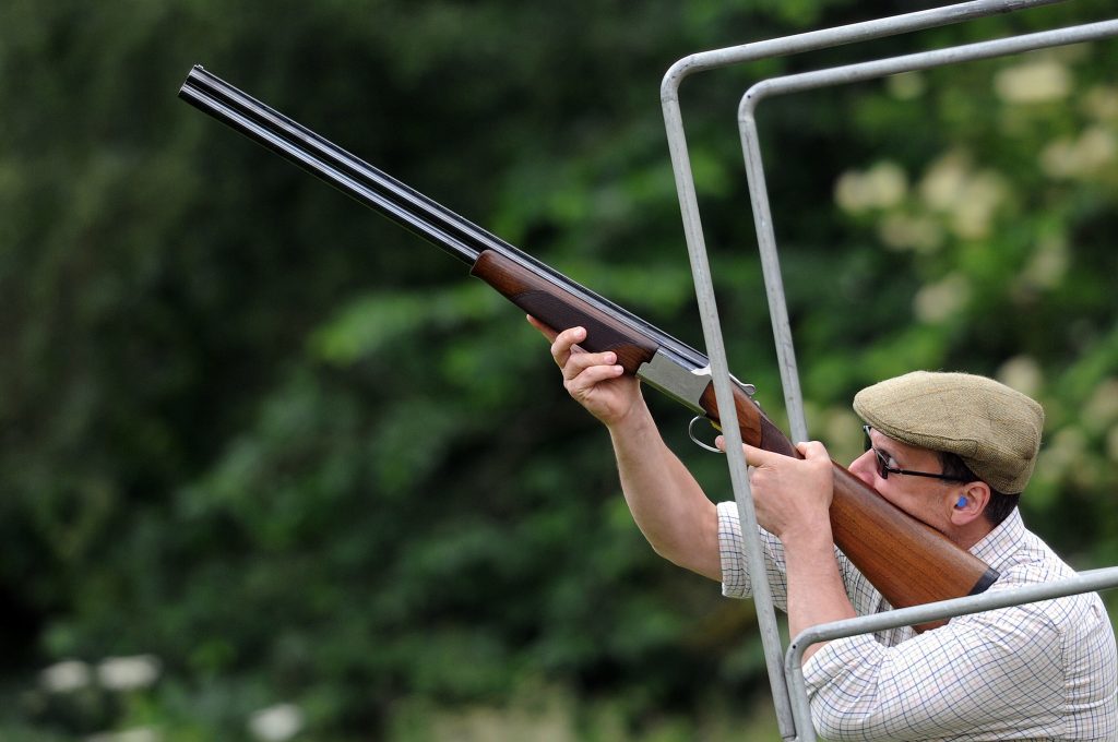 Person pointing shotgun in air at clay pigeon shoot