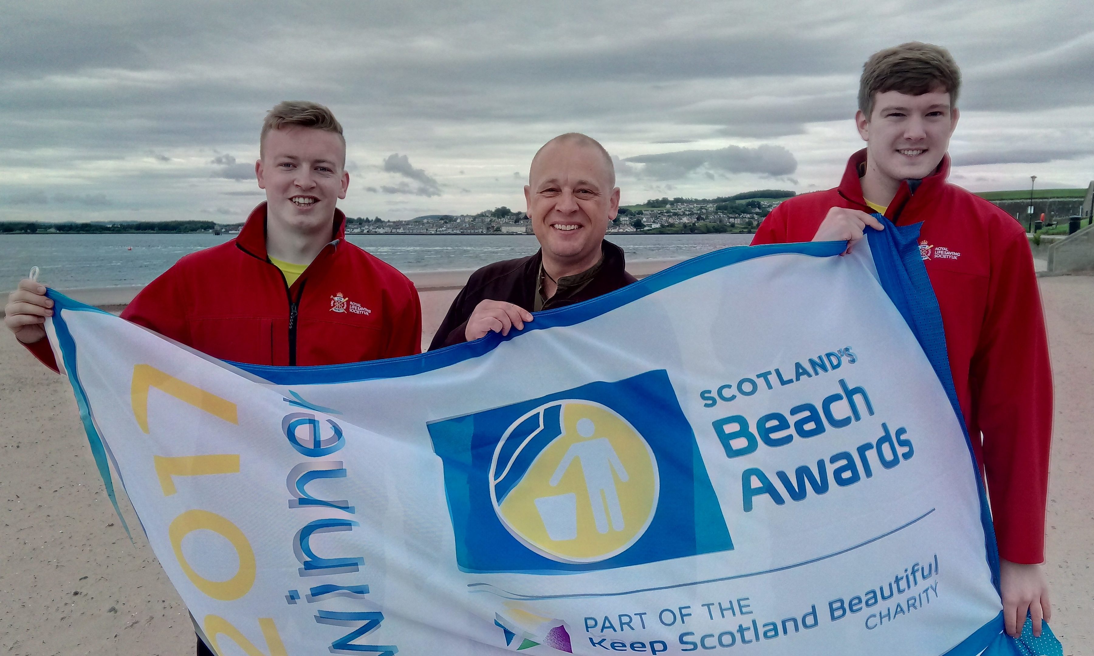 Lifeguards Kyle Doull and Sam Muir celebrate with Councillor Cordell.