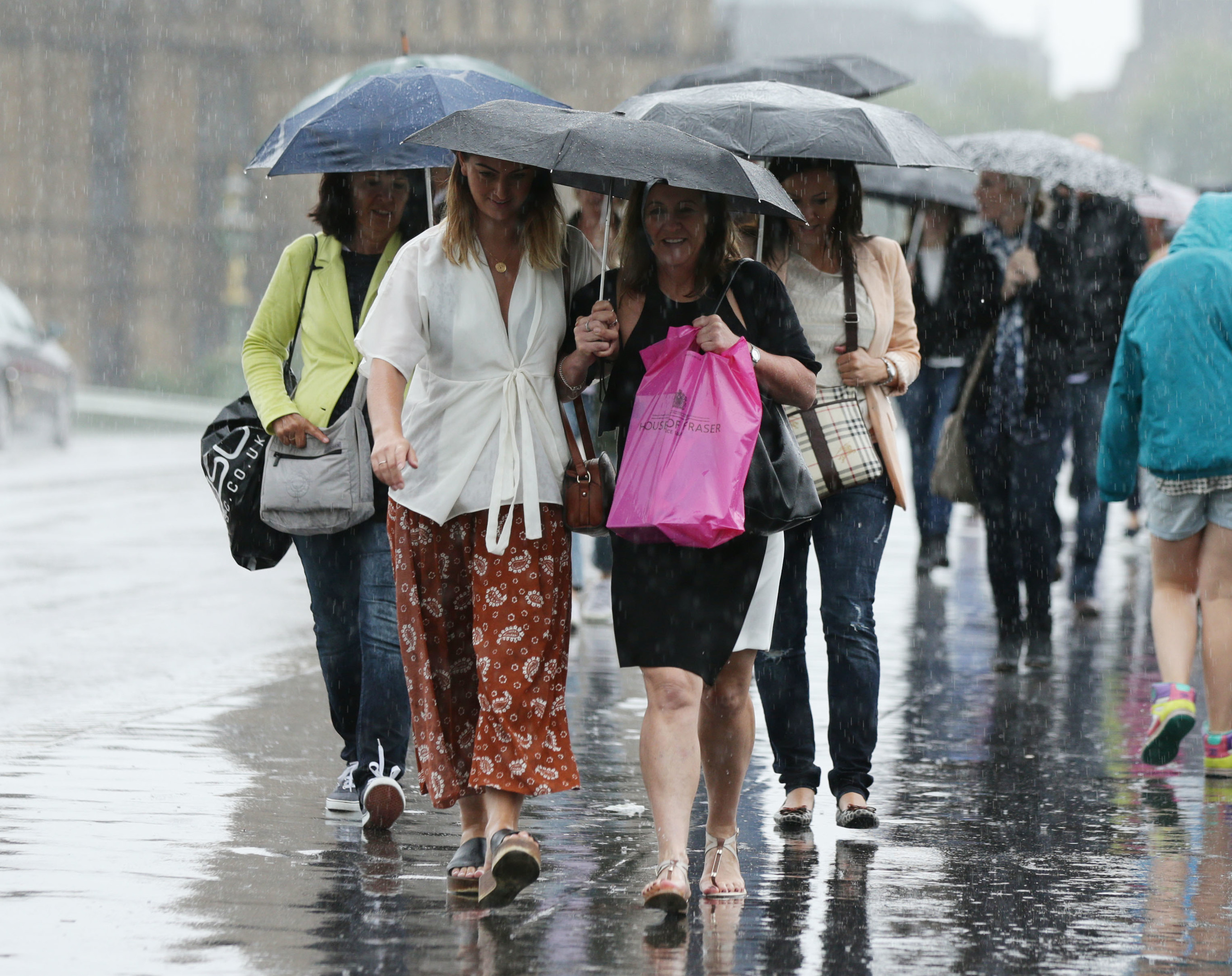 People shelter under umbrellas during heavy rain.