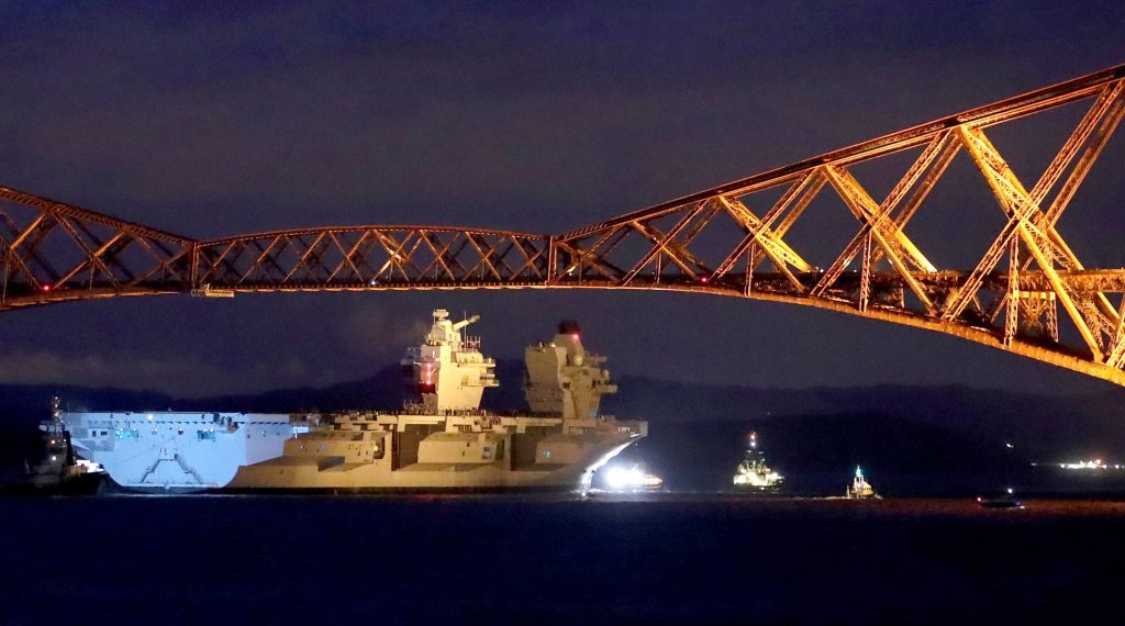 The HMS Queen Elizabeth is pulled under the Forth Rail Bridge.