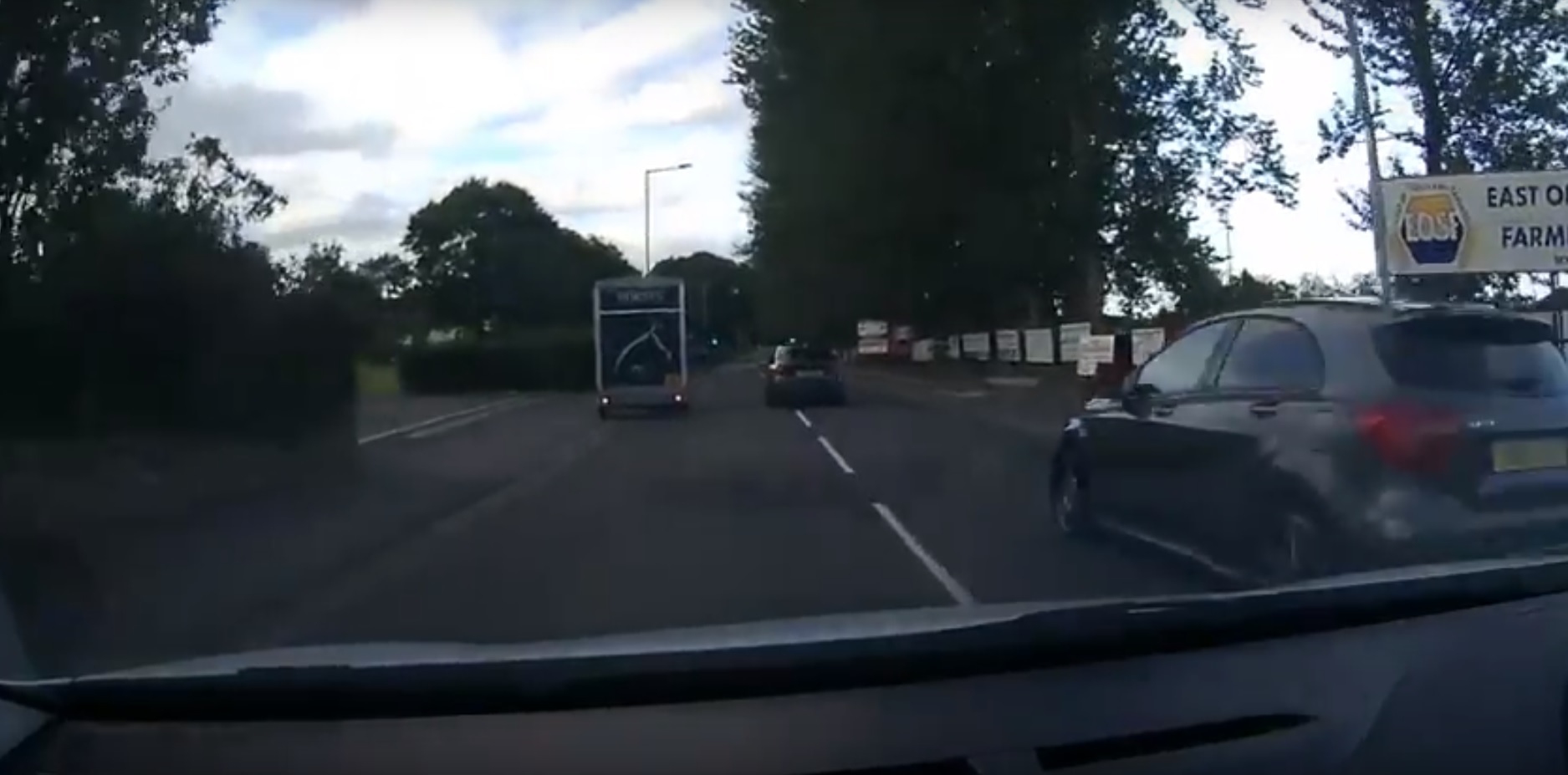 The silver vehicle passes after the dash cam vehicle has already moved out to pass the stationary horsebox.
